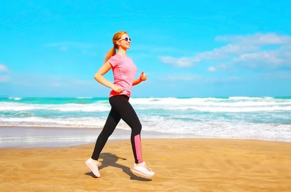 Fitness mulher está correndo verão ao longo da praia perto do mar em — Fotografia de Stock