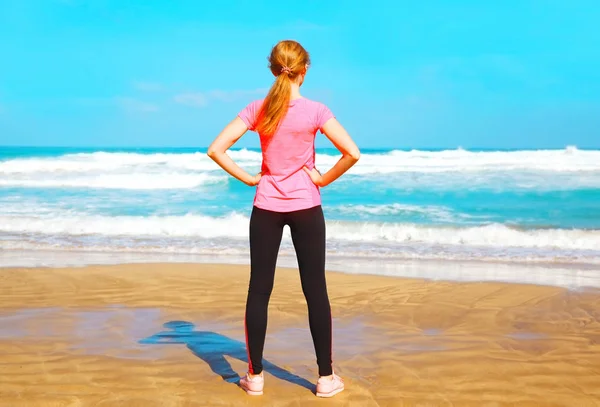 Mulher fitness fica de costas para a praia perto do mar em — Fotografia de Stock