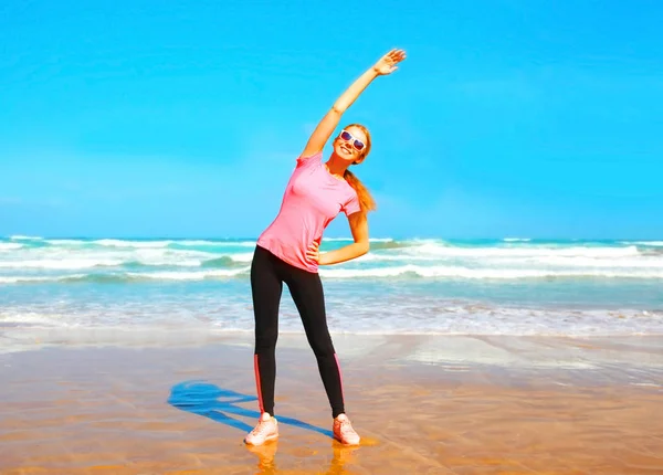 Fitness jovem fazendo exercício de alongamento na praia perto — Fotografia de Stock