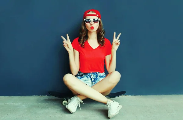 Cool young woman sitting on skateboard showing peace sign gestur — 스톡 사진