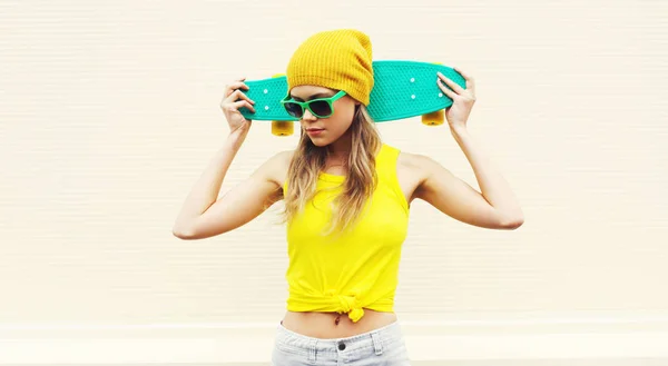 Retrato mulher legal com skate vestindo chapéu amarelo colorido — Fotografia de Stock