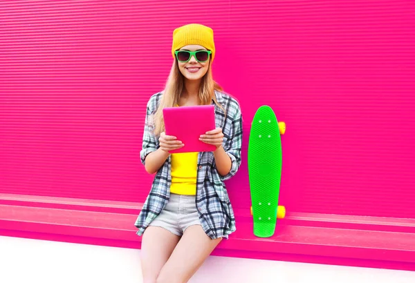 Legal jovem mulher usando tablet pc com skate vestindo colorfu — Fotografia de Stock