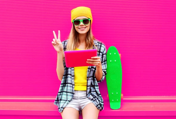 Cool giovane donna utilizzando tablet pc con skateboard indossando colorfu — Foto Stock