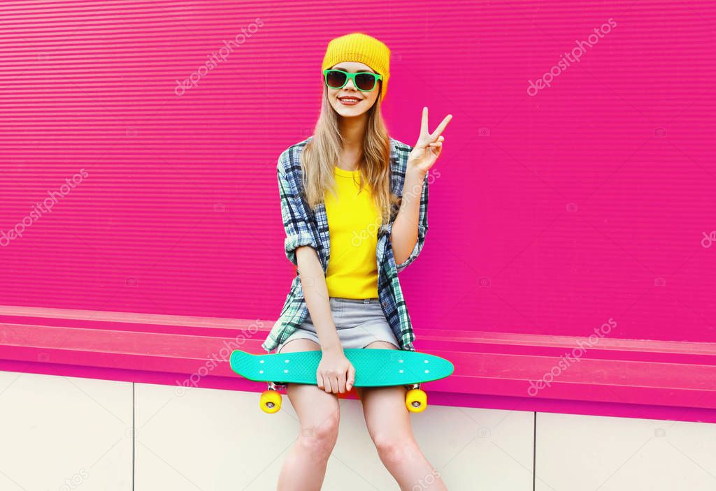 cool smiling woman with skateboard showing peace sign gesture we