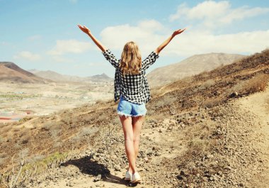 Mutlu genç kadın, dağların tepesindeki yürüyüş yolunda ellerini kaldırıyor, arkadan, Tenerife, Kanarya Adaları, İspanya