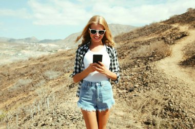 Tenerife, Kanarya Adaları, İspanya 'daki dağların tepesinde yürüyüş parkurunda telefonu olan genç bir kadın.