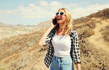 Genç, gülen bir kadın akıllı telefondan arıyor. Dağın tepesindeki yürüyüş parkurunda, Tenerife, Kanarya Adaları, İspanya