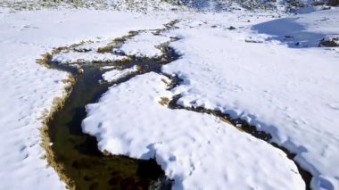 JULIERPASS, SWitzERLAND - 14 Aralık 2015: Julier dağ geçidinin altındaki karlı bir derenin üzerindeki bir dron uçuşu Graubunden kantonunda.