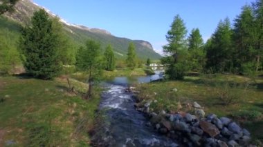 PONTRESINA, SWitzERLAND - 6 Haziran 2015: Morteratsch kampının eteğindeki göle akan akarsulardan birinin üzerinde alçak bir drone uçuşu. Ters uçuş.