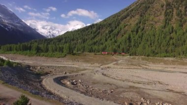 PONTRESINA, SWitzERLAND - 6 Haziran 2015: Karlı Morteratsch Buzulu 'na giden vadi. Kırmızı Bernina Ekspres treni vadinin kıyısından geçiyor.