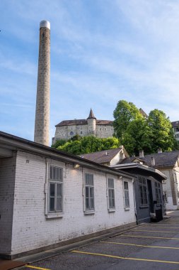 Burgdorf, İsviçre - 9 Mayıs 2020: Burgdorf 'taki eski fabrikanın bacası ve binası, ve tepenin arkasında kaleyi görebilirsiniz.
