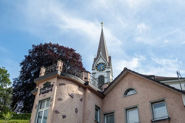 USTER, SWitzERLAND - 7 Mayıs 2020 Uster 'deki Protestan kilisesinin çan kulesi, bir iskan evinin arkasında duruyor.