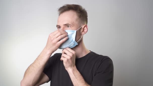 Ein Mann Setzt Sich Eine Medizinische Maske Auf Schaut Weg — Stockvideo