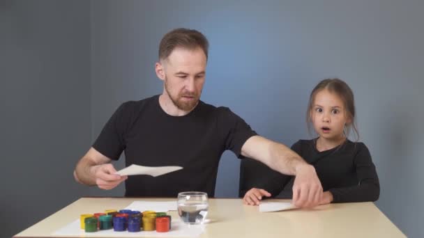 Тато Вчить Доньку Малювати Кольоровими Фарбами Одягаючись Чорне Сірому Фоні — стокове відео
