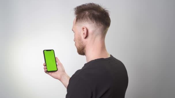 Tipo Sostiene Teléfono Con Fondo Verde Volteando Teléfono Inteligente Está — Vídeos de Stock