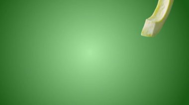 Dilimlerin yeşil arkaplana düştüğü avokado