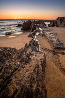 Galiçya 'daki Furnas Sahili' nde gelgit, kaya oluşumları ve arka planda gün batımı