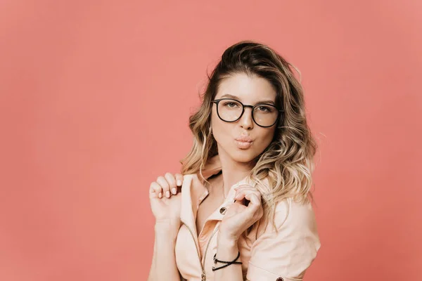 Gözlüklü, açık pembe deri ceketli, pembe arka planda öpüşen genç, kıvırcık, sarışın bir kadının portresini yakından çek. Vogue ve alışveriş.