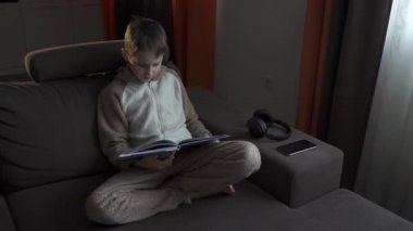 Genç çocuk kanepede oturmuş kitap okuyor. Kitabı kapatır ve dinlenir. Karantina 2020