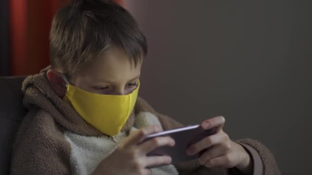 Tonårskillen i skyddsmask med en telefon i händerna. Coronavirusepidemi 2020. — Stockvideo