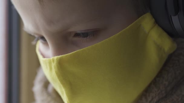 保護マスクの少年は携帯電話を手に窓辺に座っている。カラトニン — ストック動画