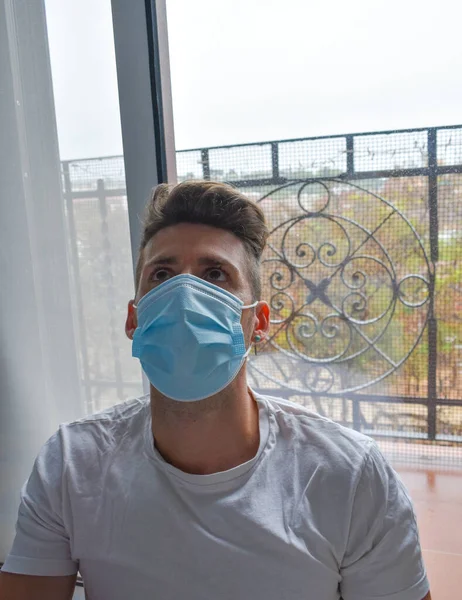 Face of a man with surgical mask in quarantine in his own home, coronavirus