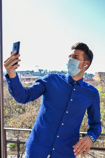 Человек Карантине Хирургической Маске Голубой Рубашкой Видеозвонком Через Мобильный Телефон — стоковое фото