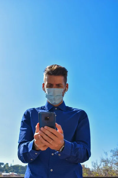 Человек Карантине Хирургической Маске Голубой Рубашкой Видеозвонком Через Мобильный Телефон — стоковое фото