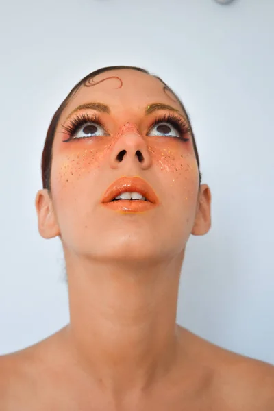 Young woman with freckles posing for some photos made up with orange colors