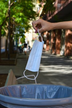 Kadın, Coronavirus 'u geride bırakmanın sembolü olarak yüz maskesi atıyor.