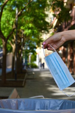 Kadın, Coronavirus 'u geride bırakmanın sembolü olarak yüz maskesi atıyor.