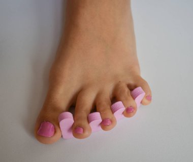 Ayak ve ellerin tırnaklarına pembe oje sürerek pedikür yaptıran bir kadın.