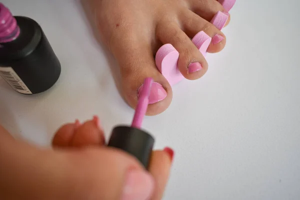 足と手の爪にピンクのネイルポリッシュを入れて ペディキュアを持っている女性の足 — ストック写真