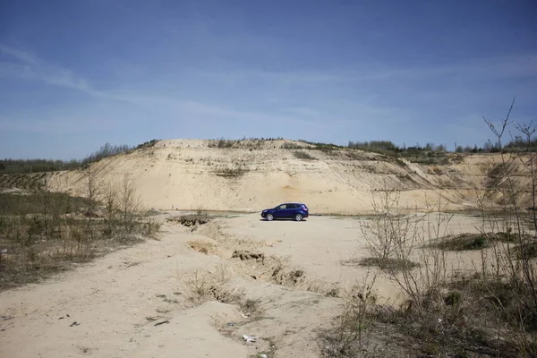 Mavi araba çöle park edilmiş.