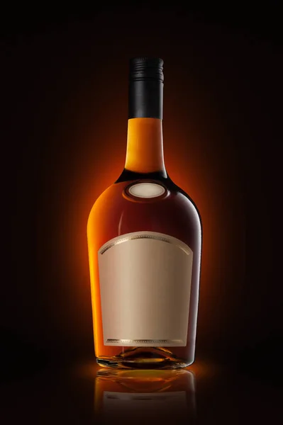 Generic brandy bottle with empty label on a dark background with orange spotlight. Vertical shot.