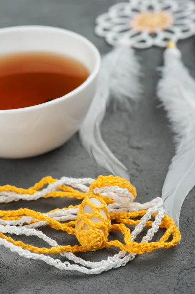 Tasse schwarzen Tee und gehäkelte Kieselsteine — Stockfoto