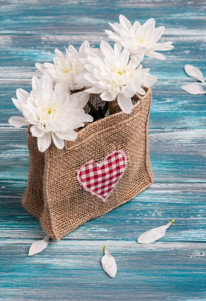 Coração têxtil e buquê de flores em saco de serapilheira áspera — Fotografia de Stock