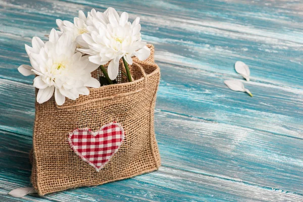 Текстильное сердце и букет цветов в грубом мешочке — стоковое фото