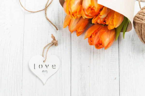 Tarjeta de felicitación de primavera con tulipanes naranjas, corazón de madera —  Fotos de Stock