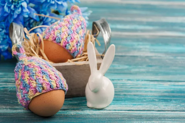Eier in Strickmützen, Blumen und dekorativen Kaninchen — Stockfoto