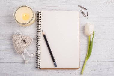 Açık defter, kalem, mum, earpods ve Lale