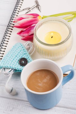 Açık defter, kahve, mum, earpods ve Lale
