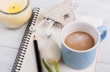 Açık defter, kahve, mum, earpods ve Lale