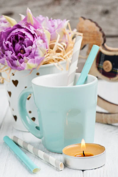 Pink tulips, blue cup, straws, lit candle and rocking horse — Stock Photo, Image