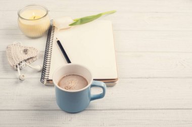 Açık defter, kalem, mum, earpods ve Lale