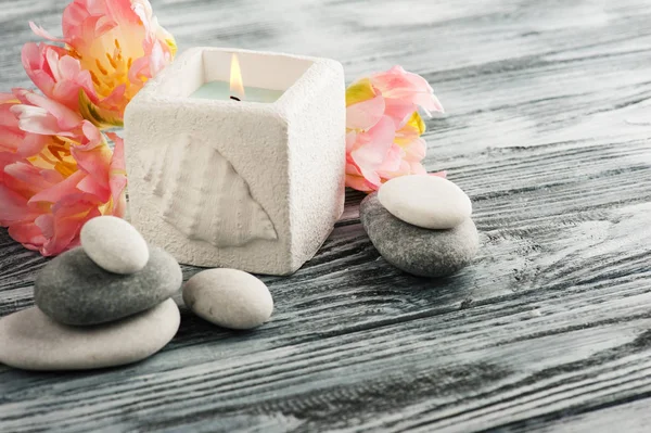 Candle and pebbles over shabby wooden background — Stock Photo, Image