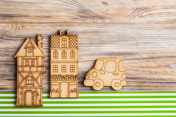 Wooden car and houses on green stripes background
