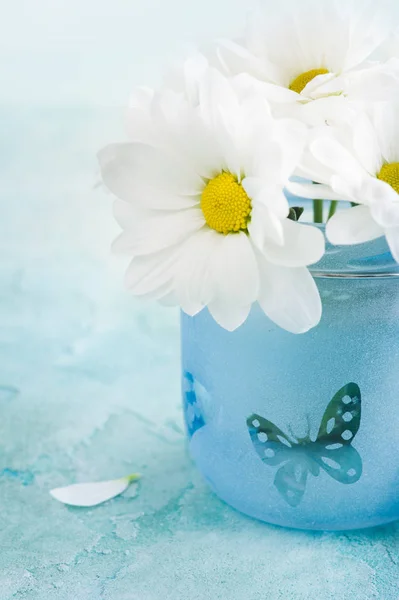 Flores frescas de margarida em vidro azul — Fotografia de Stock