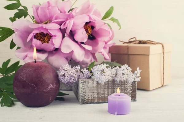 Lit velas, peônias e flores lilás — Fotografia de Stock