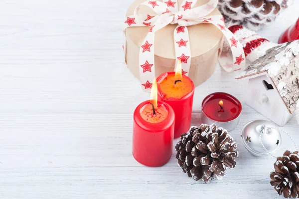 Geschenk in Kraftbox mit rotem Sternenband, brennenden Kerzen und Deko — Stockfoto